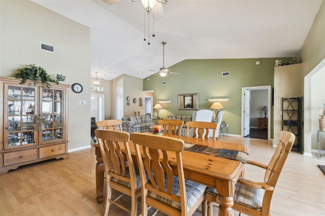 dining space featuring ceiling fan, high vaulted ceiling, and light wood-type flooring