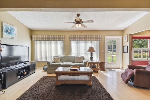 living room with ceiling fan, light hardwood / wood-style floors, and a textured ceiling