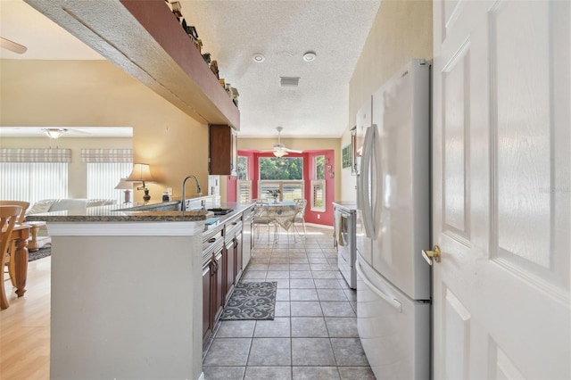 kitchen featuring ceiling fan, sink, a textured ceiling, white appliances, and light tile patterned floors