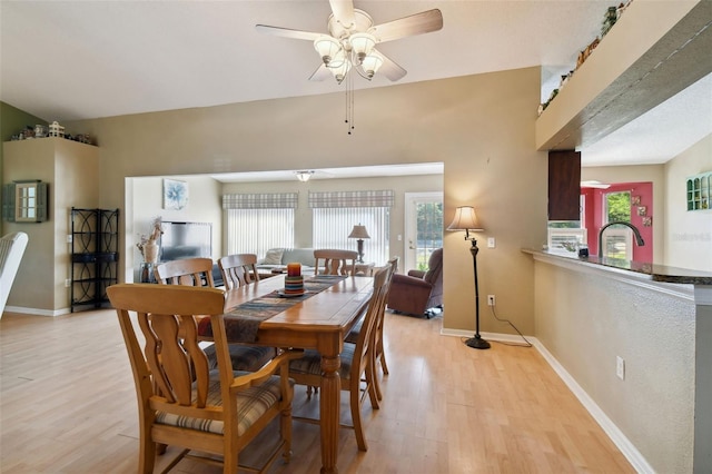 dining room with ceiling fan, light hardwood / wood-style floors, and vaulted ceiling