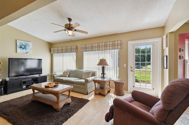 living room featuring vaulted ceiling, ceiling fan, light hardwood / wood-style floors, and a textured ceiling