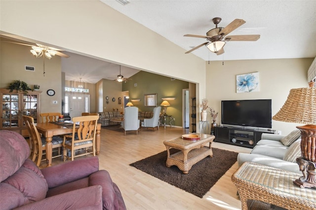 living room featuring light hardwood / wood-style floors, a textured ceiling, and high vaulted ceiling