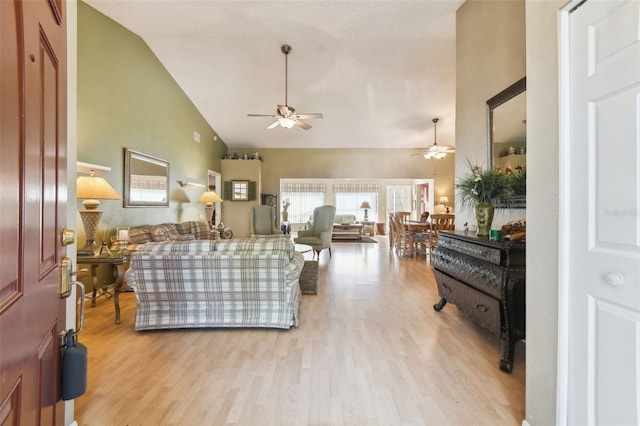 living room featuring ceiling fan, light wood-type flooring, and high vaulted ceiling