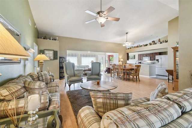 living room featuring light wood-type flooring, high vaulted ceiling, ceiling fan, and sink