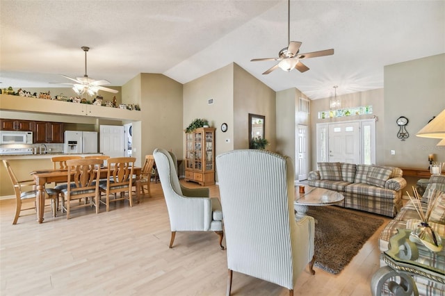 living room featuring ceiling fan, light hardwood / wood-style floors, and high vaulted ceiling