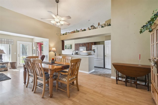 dining area featuring light hardwood / wood-style floors, high vaulted ceiling, and ceiling fan