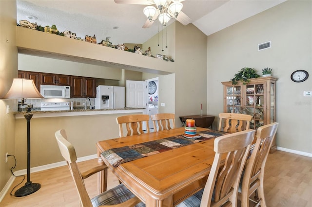 dining space featuring light hardwood / wood-style floors, high vaulted ceiling, and ceiling fan