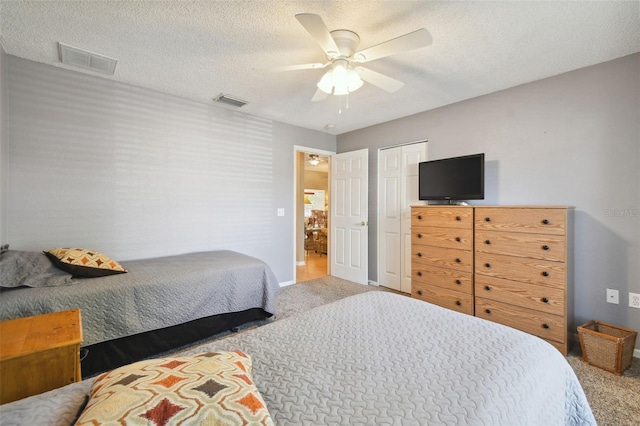 carpeted bedroom with ceiling fan, a textured ceiling, and a closet