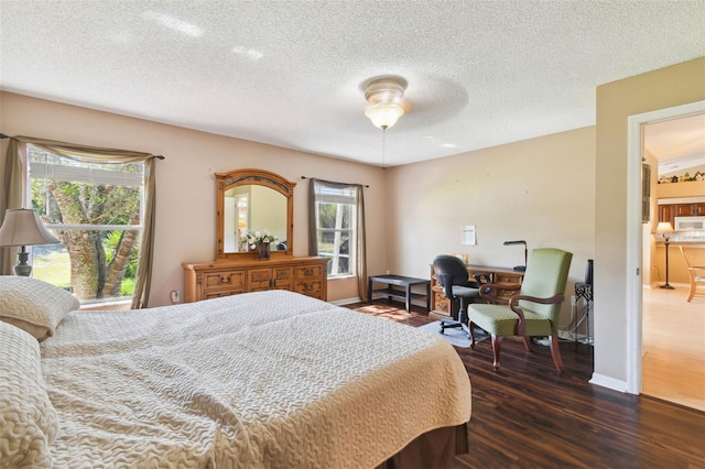 bedroom with a textured ceiling, ceiling fan, and dark wood-type flooring