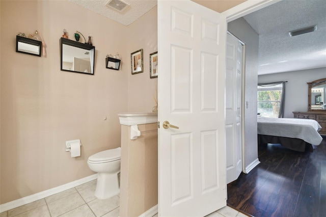 bathroom featuring tile patterned floors, toilet, and a textured ceiling