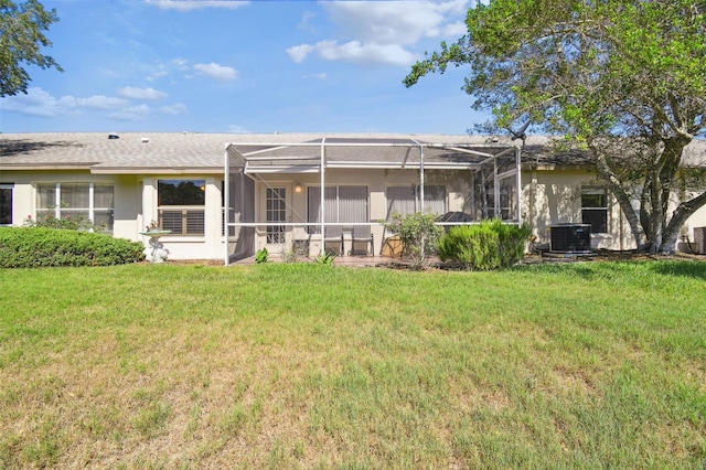 rear view of property with a lawn, glass enclosure, and central AC