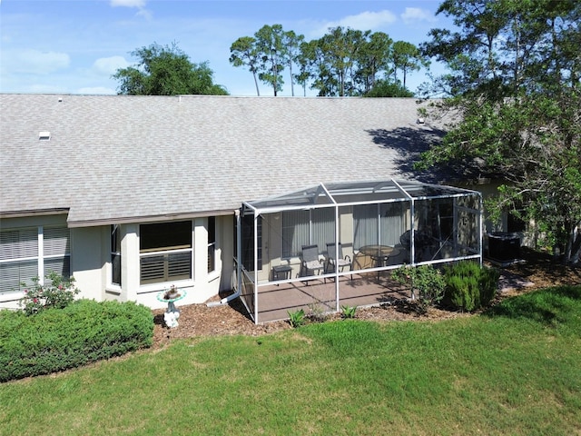 rear view of house featuring glass enclosure, a patio area, and a yard