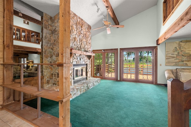 unfurnished living room featuring ceiling fan, french doors, high vaulted ceiling, beamed ceiling, and a fireplace