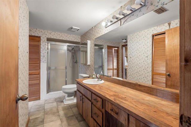 bathroom featuring tile patterned floors, vanity, toilet, and a shower with shower door