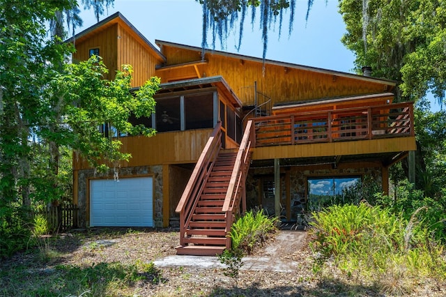 rear view of property featuring stone siding, an attached garage, stairway, and dirt driveway