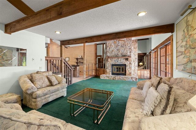 living room featuring a textured ceiling, ceiling fan, beam ceiling, carpet floors, and a stone fireplace