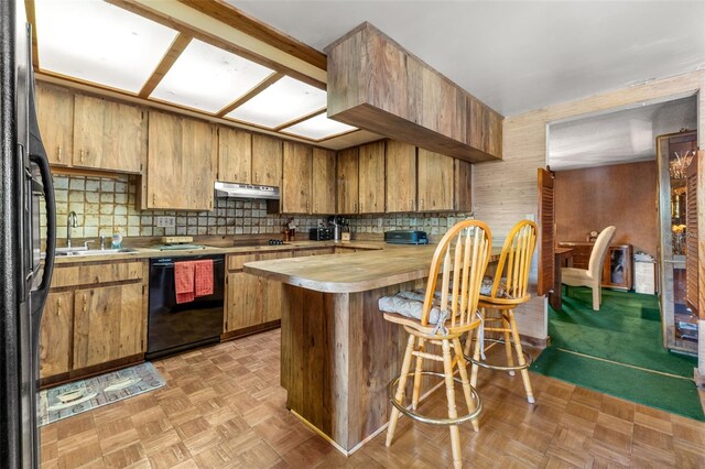 kitchen featuring kitchen peninsula, a breakfast bar, light parquet floors, sink, and black appliances