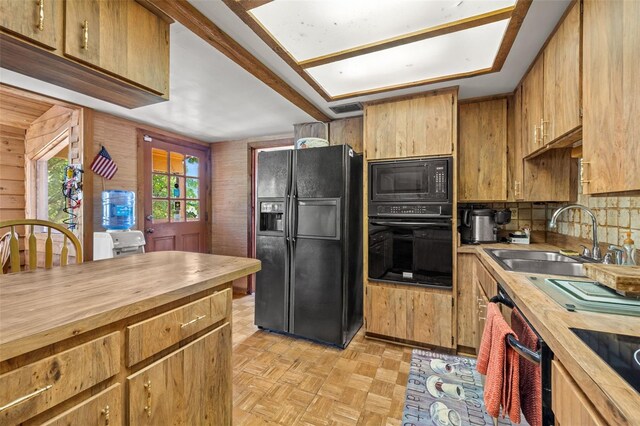 kitchen with sink, light parquet flooring, black appliances, and wood counters