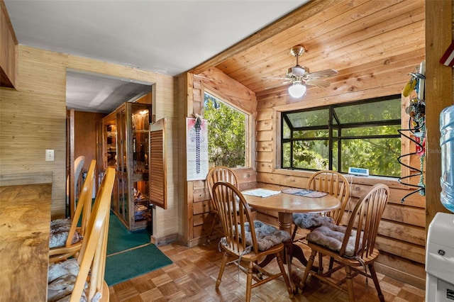 dining area with parquet floors, wooden walls, ceiling fan, and vaulted ceiling