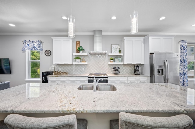 kitchen with appliances with stainless steel finishes, ornamental molding, wall chimney exhaust hood, sink, and decorative light fixtures