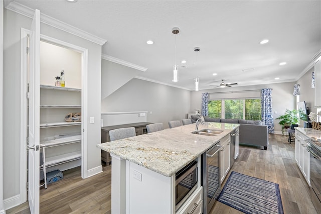 kitchen featuring sink, pendant lighting, a center island with sink, light hardwood / wood-style flooring, and white cabinetry