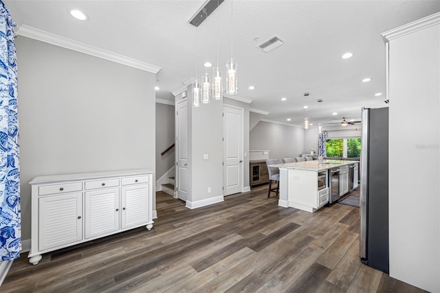 kitchen with white cabinetry, stainless steel fridge, a kitchen island with sink, and hanging light fixtures