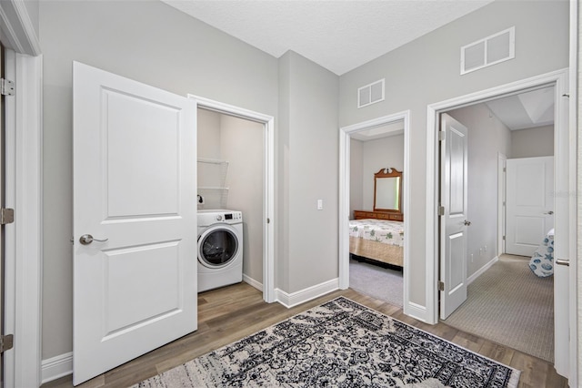 laundry room with washer / clothes dryer, wood-type flooring, and a textured ceiling