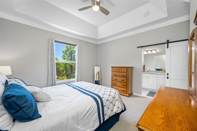 bedroom with light carpet, ensuite bathroom, a raised ceiling, ceiling fan, and a barn door