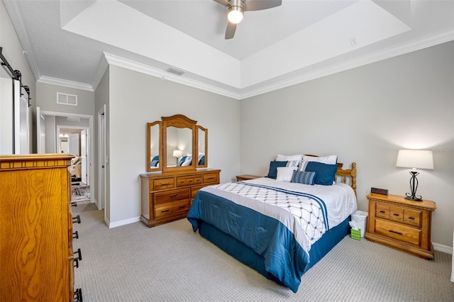 carpeted bedroom with a tray ceiling, ceiling fan, and crown molding