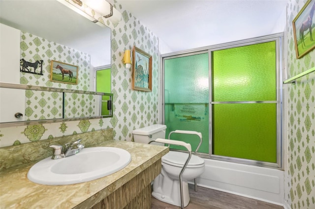 full bathroom featuring toilet, vanity, bath / shower combo with glass door, and hardwood / wood-style floors