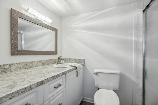 bathroom featuring toilet, vanity, and a shower with shower door