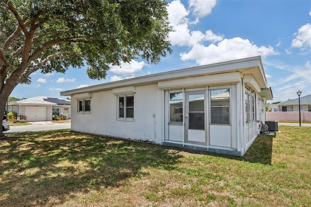 rear view of house featuring central AC and a yard