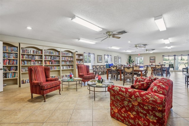 living room with a textured ceiling, ceiling fan, and light tile patterned floors