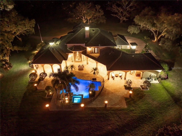 pool at night featuring a patio area