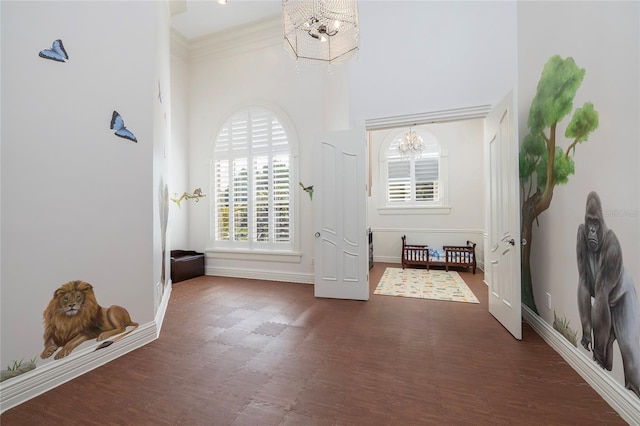 entrance foyer with dark hardwood / wood-style floors, ornamental molding, a towering ceiling, and an inviting chandelier