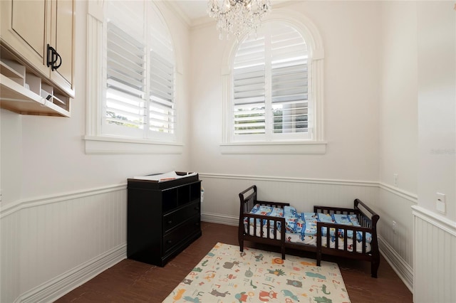 bedroom featuring dark hardwood / wood-style floors, a crib, crown molding, and a chandelier