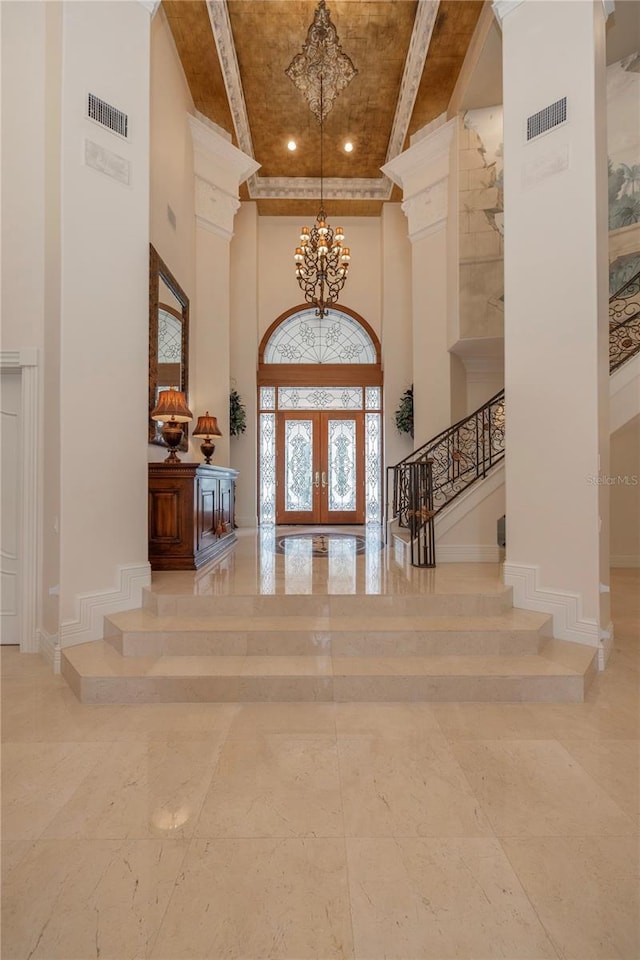 foyer with a chandelier, french doors, a towering ceiling, and beam ceiling