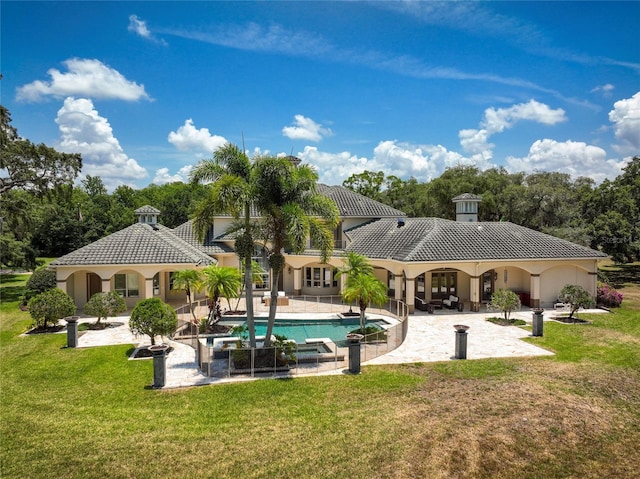 rear view of house featuring a patio, a tile roof, a pool with connected hot tub, a yard, and stucco siding