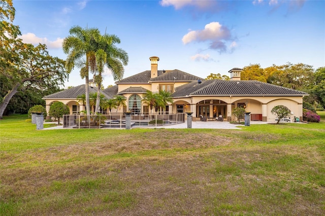 back of house featuring a patio area, a tile roof, stucco siding, and a yard