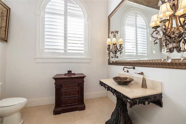 bathroom with tile patterned flooring, baseboards, and toilet