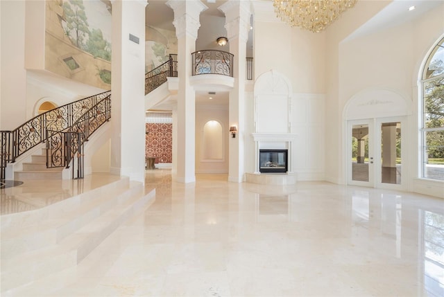 unfurnished living room with visible vents, a tiled fireplace, stairway, marble finish floor, and a high ceiling