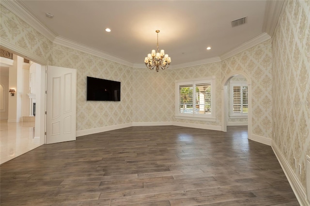 empty room featuring wallpapered walls, visible vents, arched walkways, dark wood-type flooring, and a notable chandelier