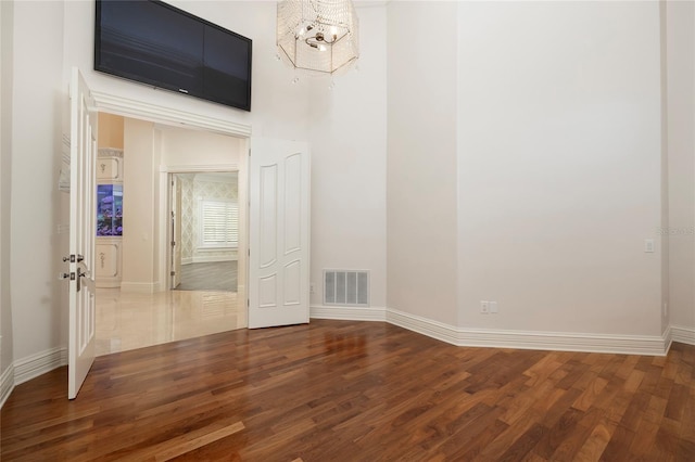 spare room featuring an inviting chandelier, baseboards, visible vents, and wood finished floors