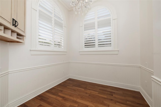 unfurnished room featuring a chandelier, wainscoting, and dark wood finished floors