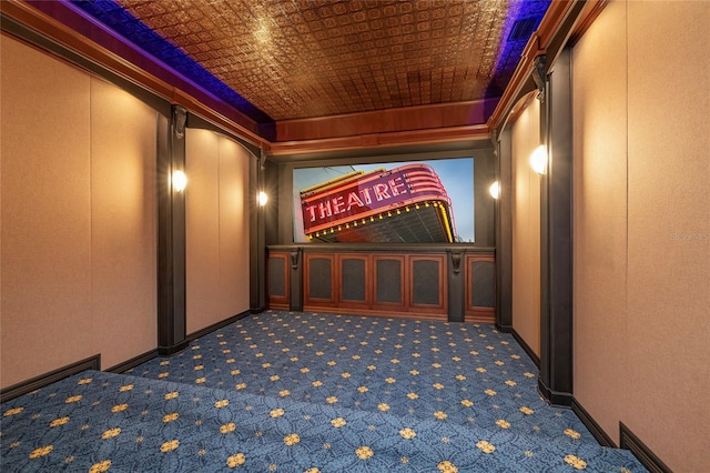 cinema room featuring an ornate ceiling, baseboards, and dark colored carpet