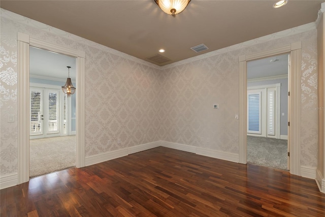 spare room featuring ornamental molding, wood finished floors, visible vents, and wallpapered walls