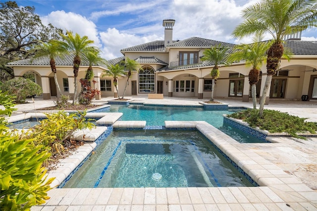 view of pool featuring a pool with connected hot tub, a patio, and french doors