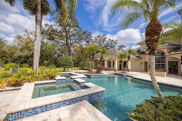 view of pool with a patio area and a pool with connected hot tub