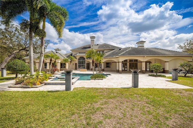 back of property featuring stucco siding, a tile roof, a lawn, and a patio