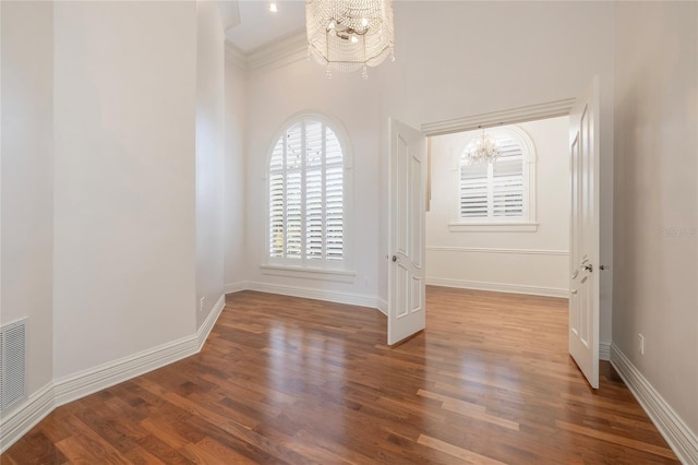 spare room featuring wood finished floors, baseboards, and an inviting chandelier